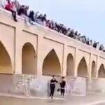 People gather along the Zayandeh Rud River in Isfahan as water flows again after years of drought, celebrating the river's return.