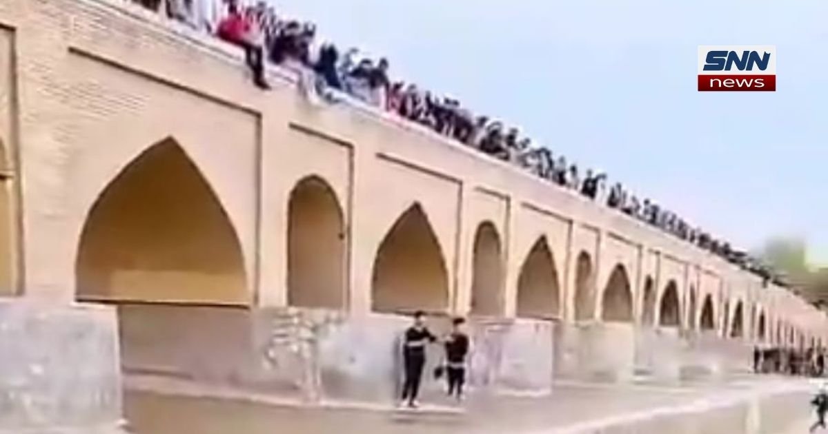 People gather along the Zayandeh Rud River in Isfahan as water flows again after years of drought, celebrating the river's return.