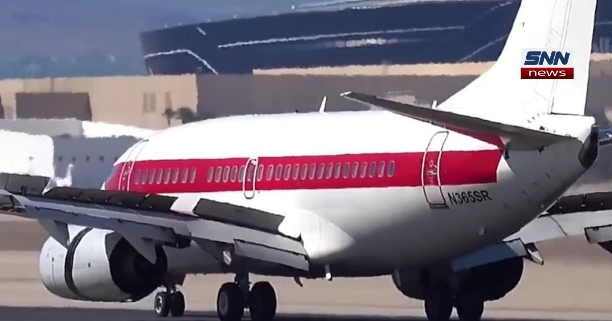 "Unmarked white Boeing 737 with red stripe on tarmac, representing JANET flights linked to Area 51"
