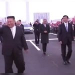 North Korea's Kim Jong Un waving as he walks with Chinese officials past students waving red flags, SNN News Finland